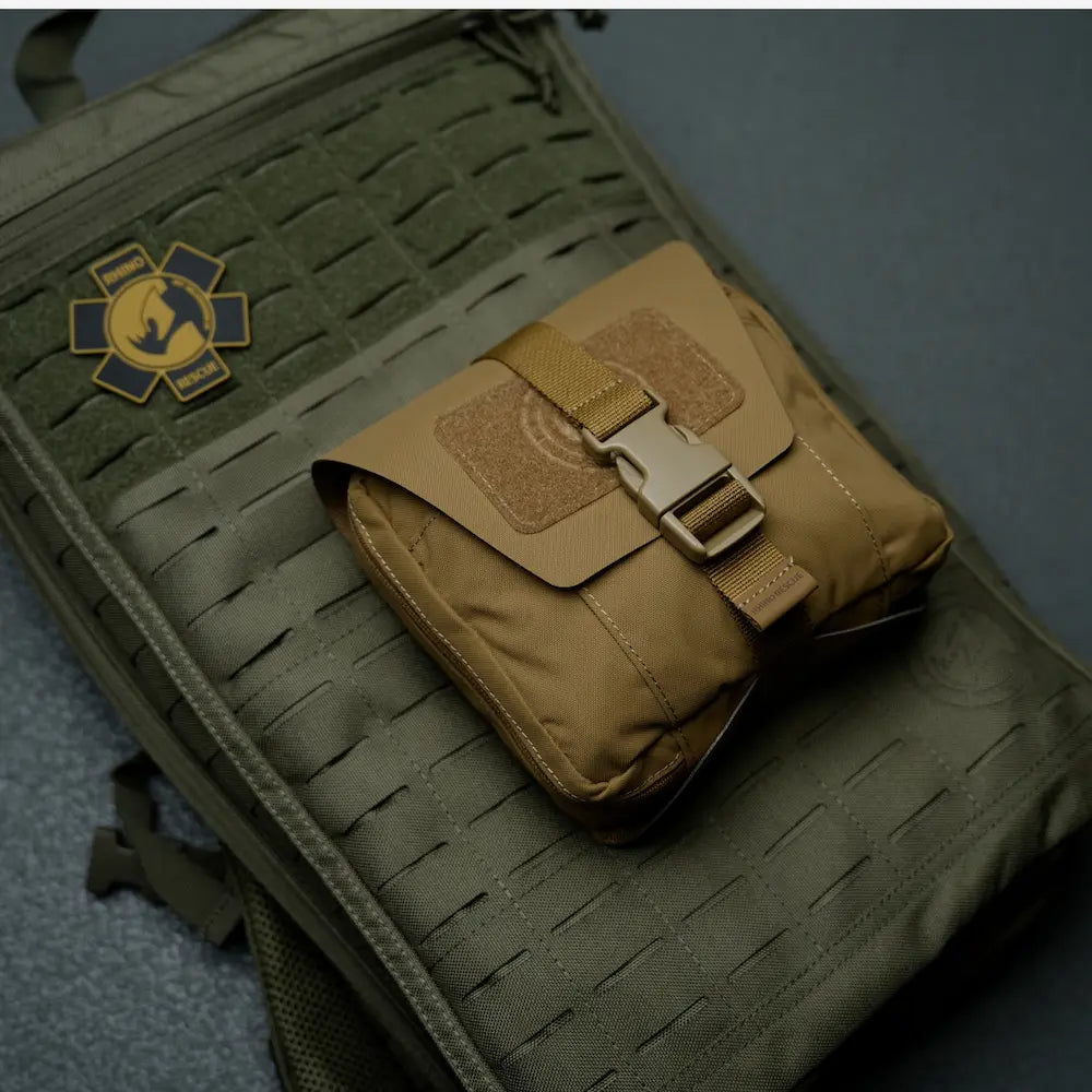 A tan tactical pouch resting on a larger olive green MOLLE bag 